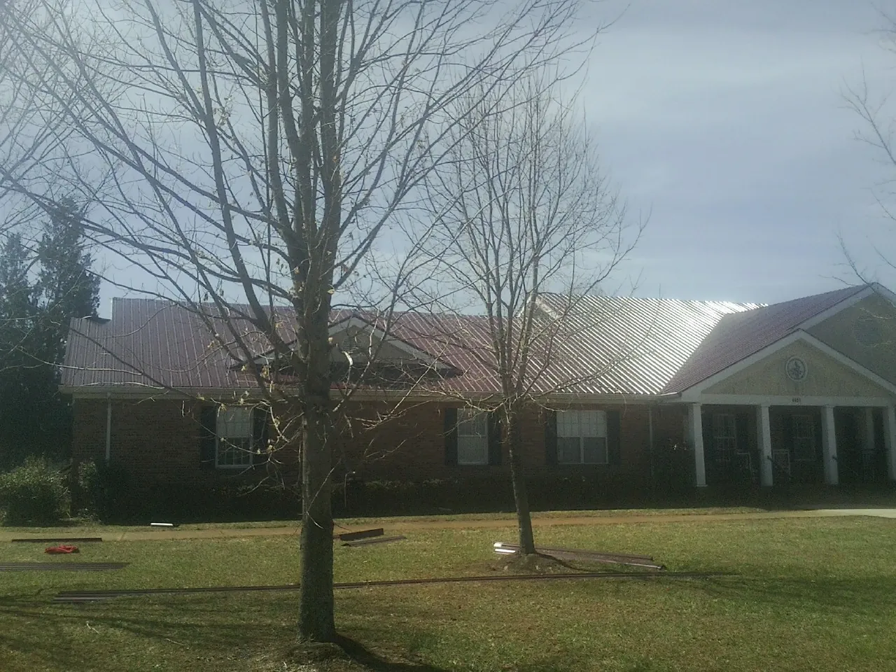 Red metal roof on a brick building seen from the front lawn in Horton