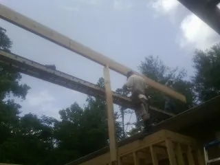 Carpenter setting a ridge beam over a new addition frame — Ice Dam Removal by Roofing Brothers in Horton